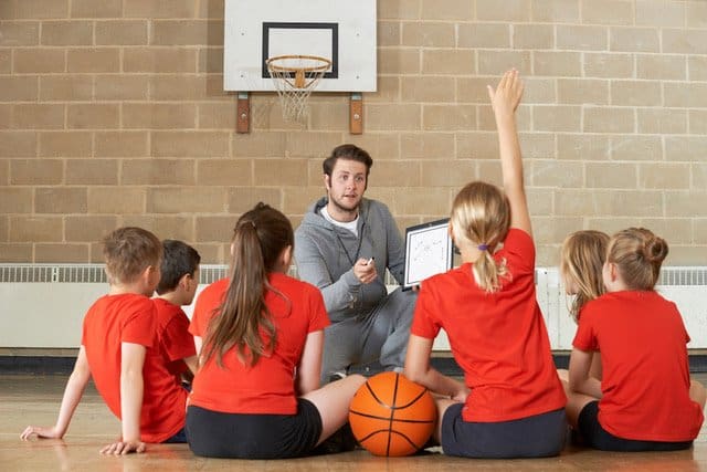 Coach Giving Team Talk To Elementary School Basketball Team