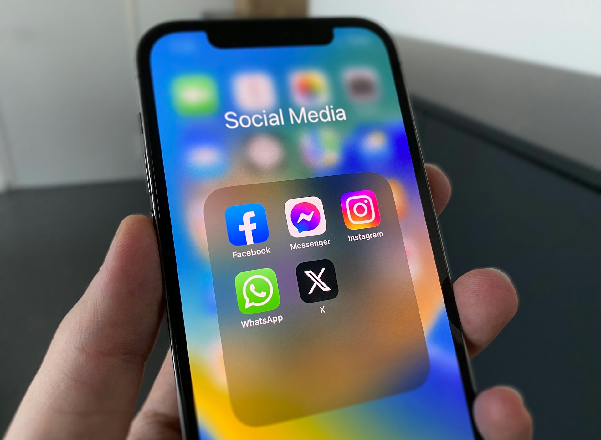 A smartphone with social media app icons like Facebook, Instagram and X shown on the screen