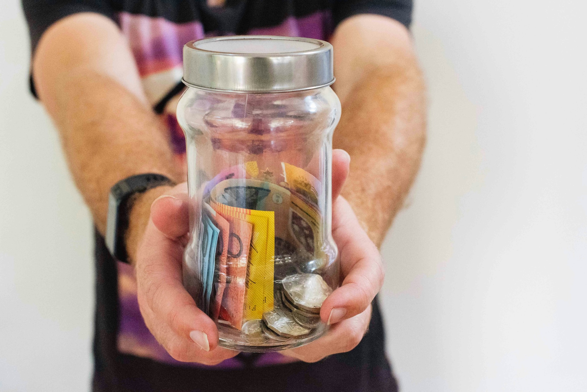 Person holding jar with Australian bank notes and coins