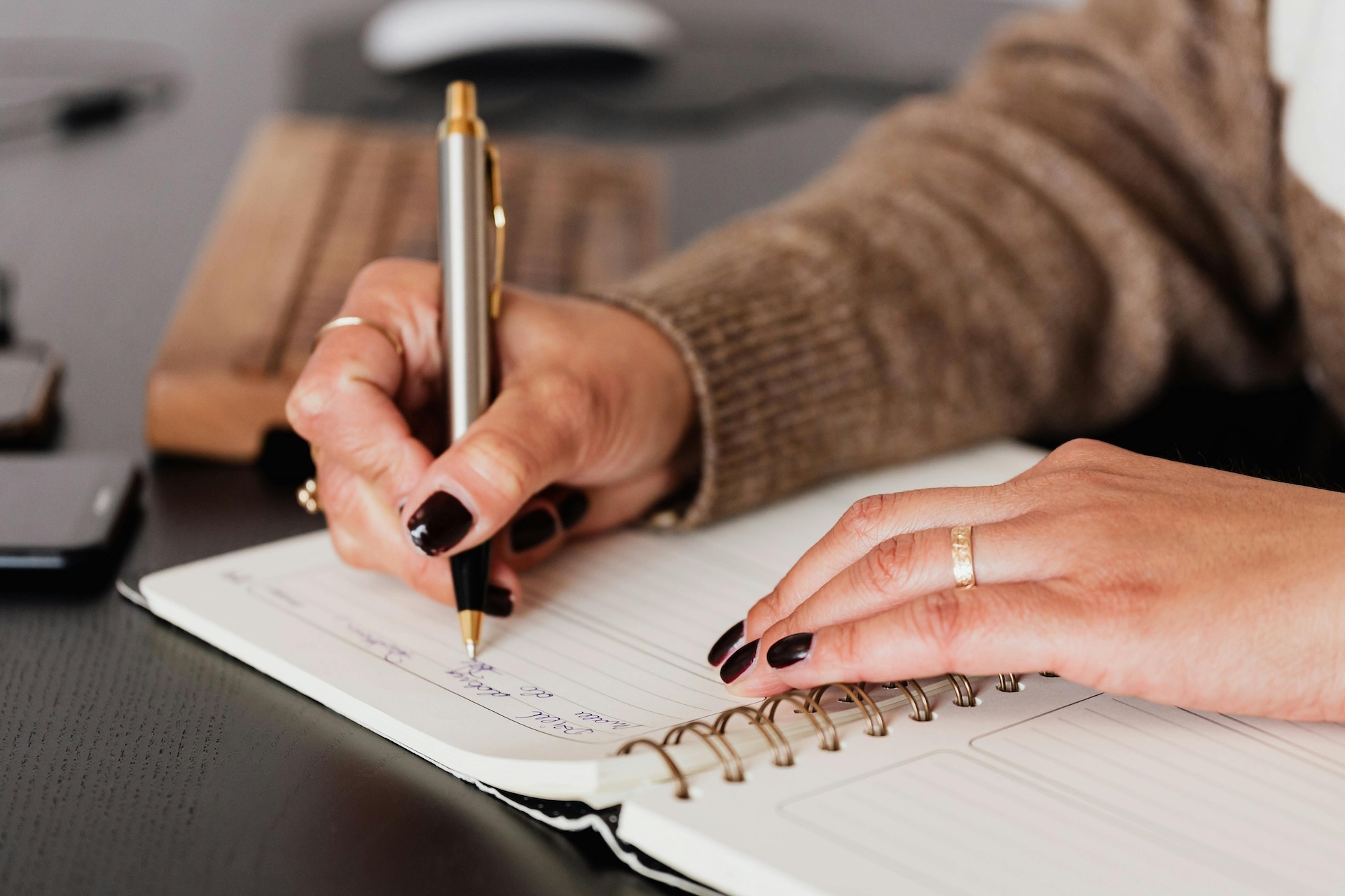 Person holding a pen writing in a diary